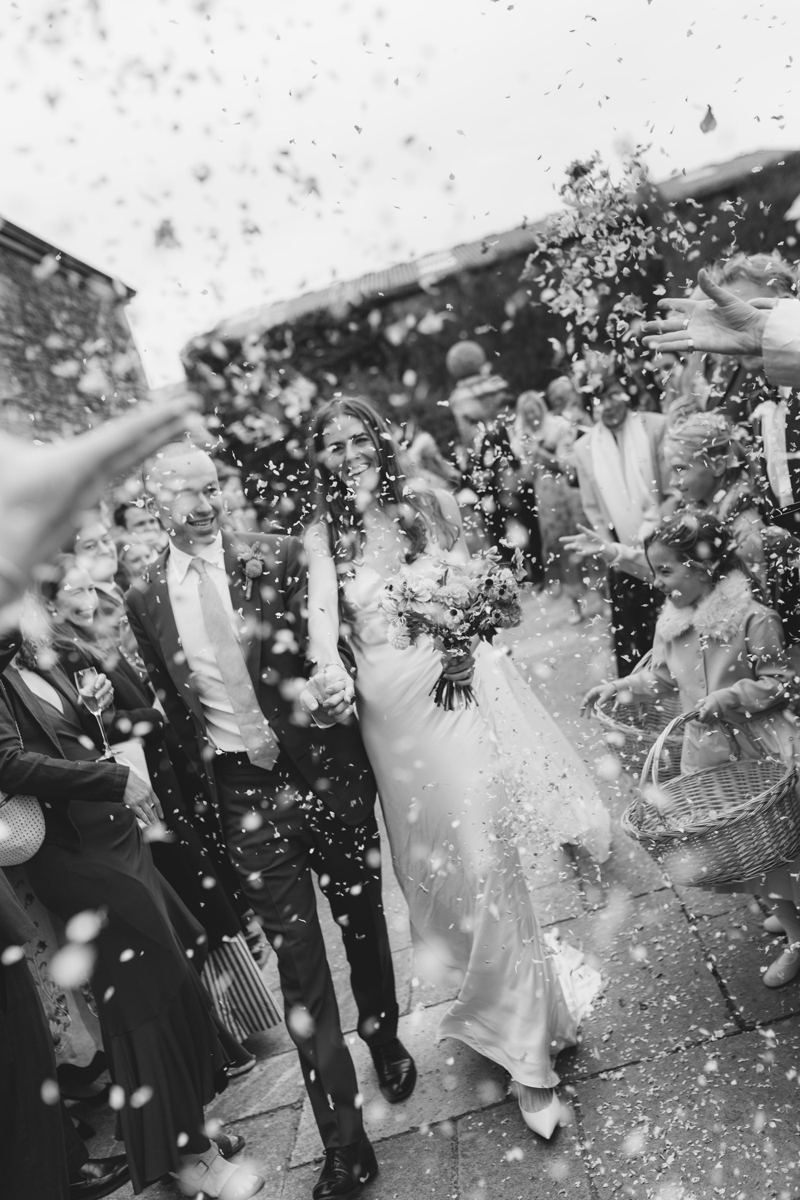 Bride and groom walking through confetti